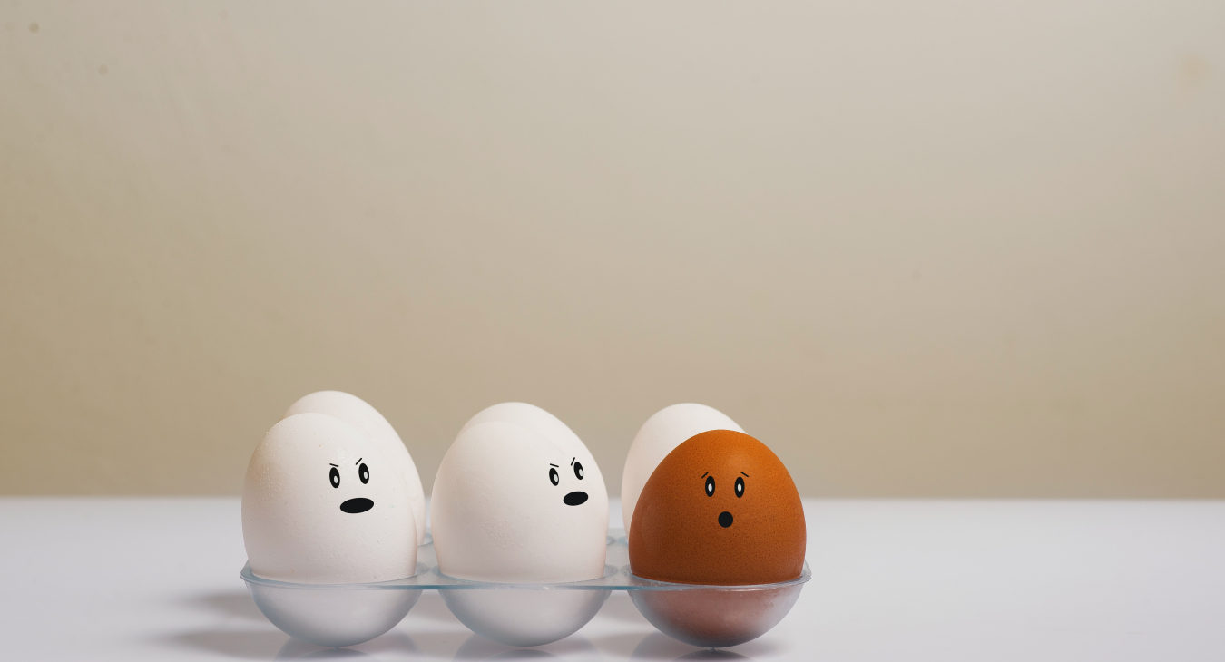 Five white eggs and one dark egg in a tray